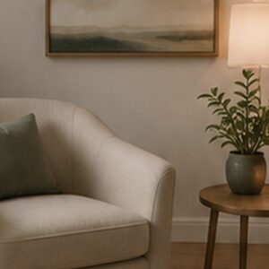 Warm consultation room detail with chair, lamp, and plant